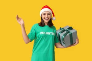 Volunteer Woman Holding A Gift With A Santa Hat
